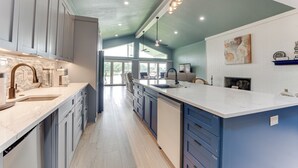 Cocina moderna con una isla grande, electrodomésticos integrados y vistas al área de comedor.