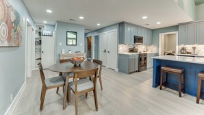Una cocina moderna con una isla central, electrodomésticos integrados y un comedor con una mesa redonda y sillas.
