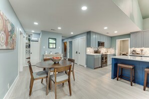 Una cucina moderna con isola centrale, elettrodomestici integrati e zona pranzo con tavolo e sedie rotonde.