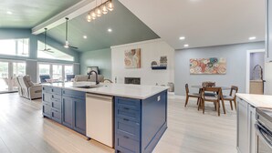 Una cocina moderna con una isla grande, electrodomésticos integrados y una zona de comedor con muebles de madera.