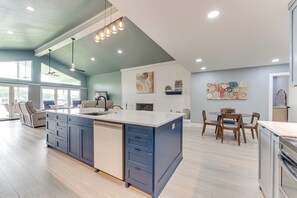 Una cucina moderna con una grande isola, elettrodomestici integrati e un'area pranzo con mobili in legno.