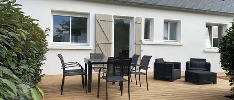 A patio with a table and chairs, a door, and windows.
