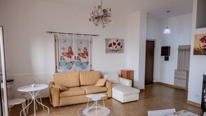Una sala de estar moderna con un sofá color beige, un sillón blanco, una mesita redonda y un tapete estampado.