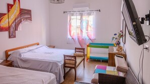 Un dormitorio con dos camas, un escritorio, una silla, un televisor y obras de arte en la pared.