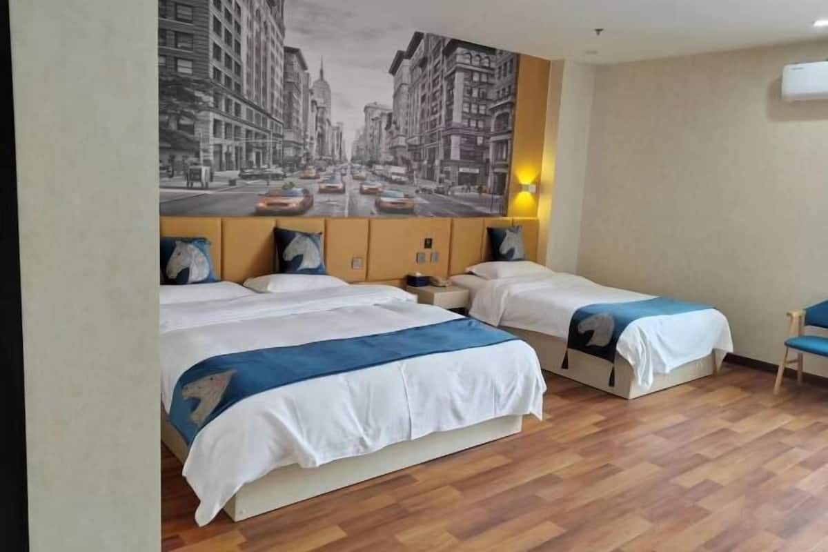 A hotel room with two beds, a large cityscape mural on the wall, a wooden floor, and a chair.