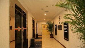 Un pasillo de hotel con piso pulido, una planta en maceta y señales de dirección en las paredes.