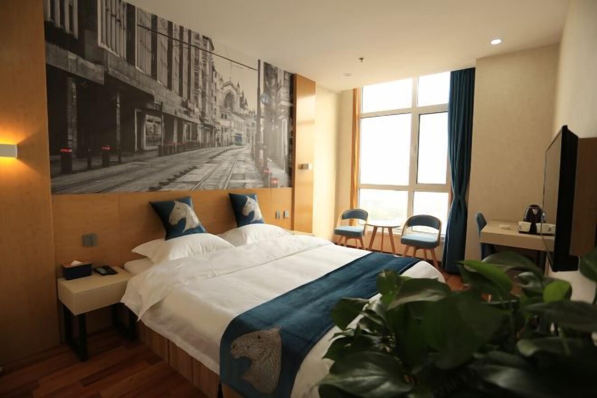 Une chambre d’hôtel avec un grand lit, un bureau, une chaise et une fenêtre avec des rideaux.
