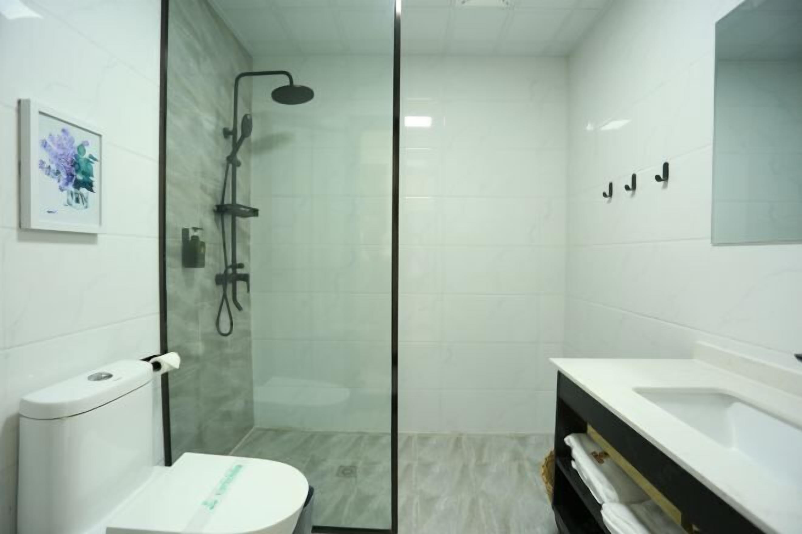 Ein modernes Badezimmer mit einer gläsernen Duschkabine, einer Toilette und einem Waschtisch mit Spiegel.
