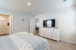 Cozy retreat with a large bed, dresser, and flat-screen TV.
