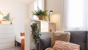 Un salon moderne avec un canapé gris, un meuble blanc et une plante posée sur une étagère.