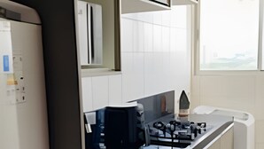 Una cocina moderna con armarios blancos, una encimera negra y un ventanal que proporciona luz natural.
