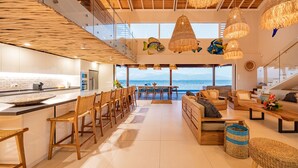 A spacious kitchen with a large island, dining area with chairs, and a seating area with sofas and a coffee table.