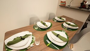 A dining table set with white plates, green napkins, and clear glasses. - APTO decorado 5 hospedes AC e piscina (Foz do Iguaçu)