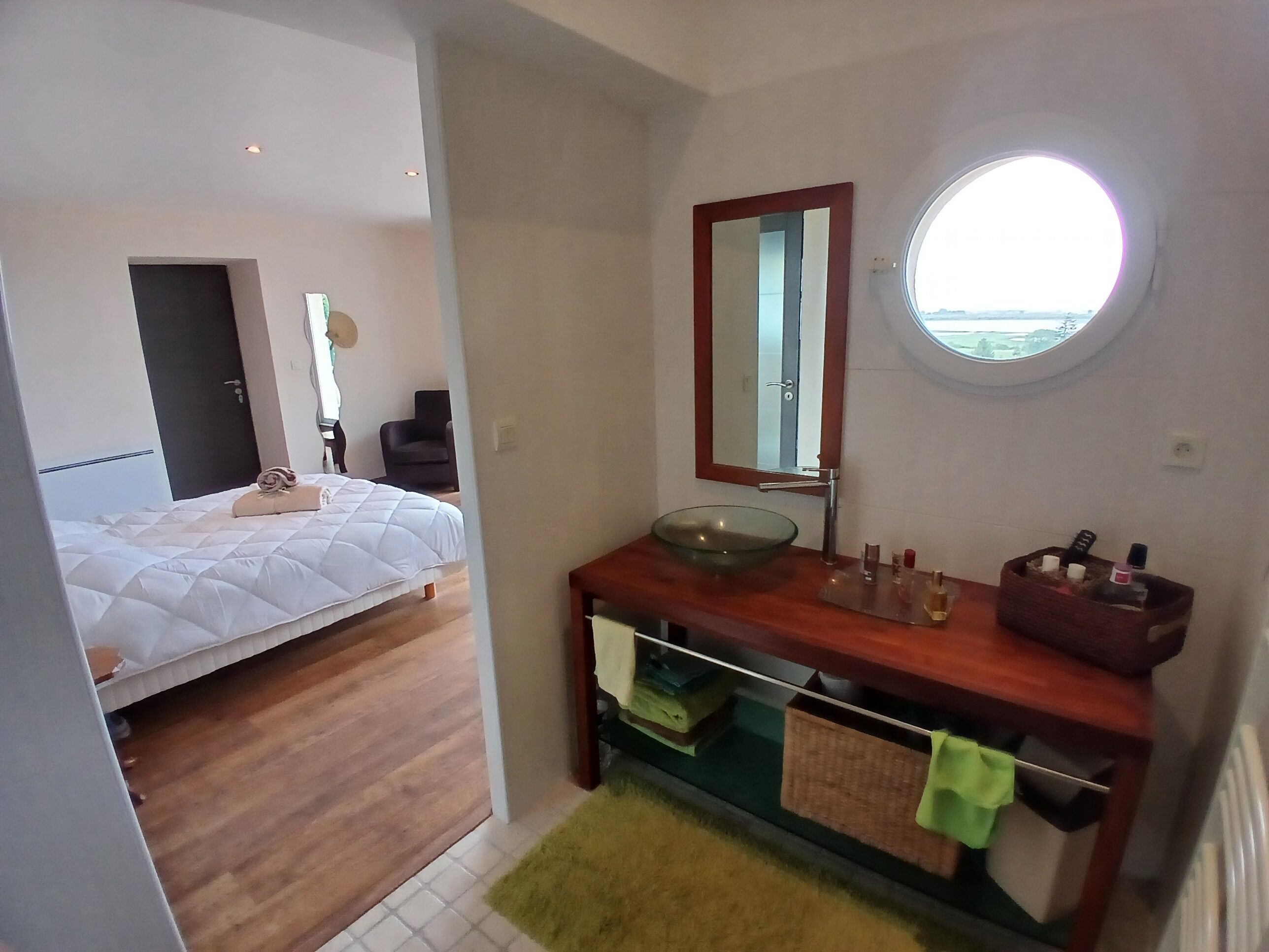 Un dormitorio con cama, mesita de noche, espejo y ventana.