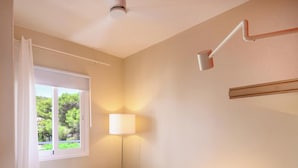 A room with a window, a lamp, and a ceiling fan. - Apartment 5 In front of the sea (Urbanització Santo Tomàs, Es Migjorn Gran)
