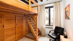 A room with a wooden bunk bed, a black leather chair, a small table with a lamp, and a window with curtains. - LECCO, 20 - In the heart of the Rainbow District. (Milan)