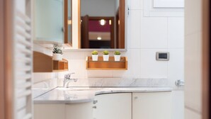 A bathroom with a white vanity, a mirror, a sink, and three potted plants on the countertop. - LECCO, 20 - In the heart of the Rainbow District. (Milan)