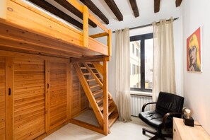 A room with a wooden bunk bed, a black leather chair, a small table with a lamp, and a window with curtains. - LECCO, 20 - In the heart of the Rainbow District. (Milan)