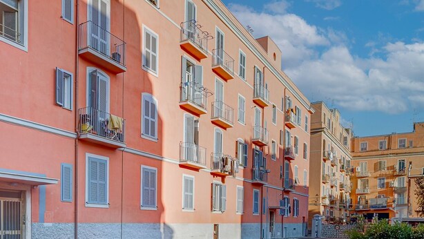 A row of multi-story buildings with balconies, a clear sky, and a street in front. - Don Leandro's House by Rentbeat (Civitavecchia)