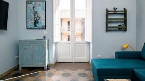 A room with a teal sofa, a wooden cabinet, a map on the wall, and a door leading to another space. - Casa Sinatra by Rentbeat (Taranto)
