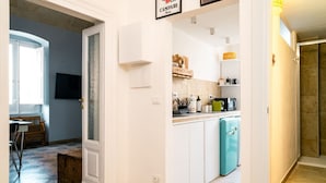 A compact kitchen with white cabinets, a teal refrigerator, and a coffee machine. - Casa Sinatra by Rentbeat (Taranto)