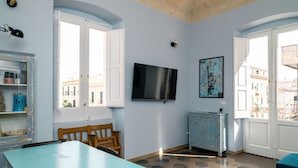 A room with a TV, a blue cabinet, a wooden chair, and a table. - Casa Sinatra by Rentbeat (Taranto)