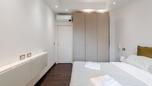 A bedroom with a bed, a wardrobe, a radiator, and a wall-mounted air conditioner. - Casa Peschiera by Rentbeat (Torino)