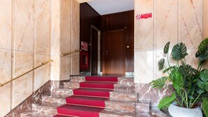 A marble staircase with red carpeted steps leading to a door. - Casa Peschiera by Rentbeat (Torino)