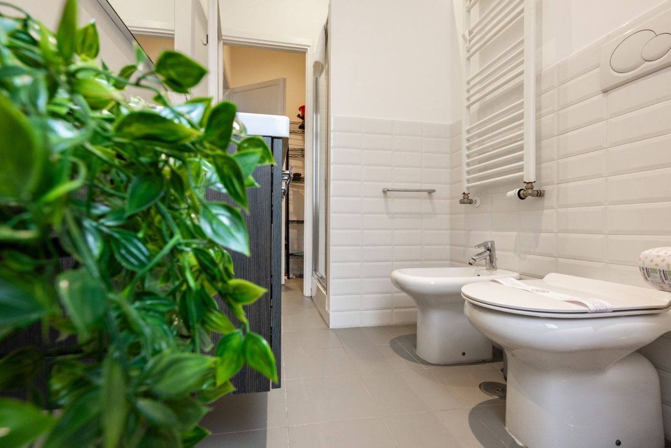 A modern bathroom with two toilets, a sink, and a shower.