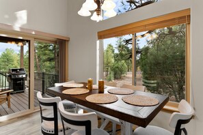 Enjoy meals with family and friends in this spacious dining area, surrounded by a lush wooded landscape.