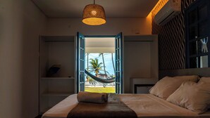 Ein Schlafzimmer mit einem Bett, einer Hängematte und Blick auf Palmen.