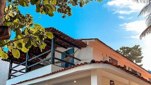 Ein zweistöckiges Haus mit Balkon, Hängematte und einer Treppe, die zu der oberen Etage führt.