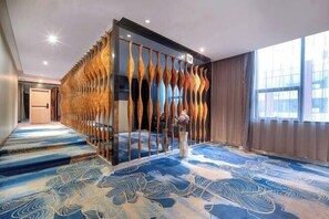A hotel room with a unique wooden partition, a patterned carpet, and a large window. - K. Y. Hotel (Liuzhou)