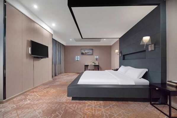 A modern hotel room with a large bed, a flat-screen TV, a desk with a chair, and a painting on the wall. - K. Y. Hotel (Liuzhou)