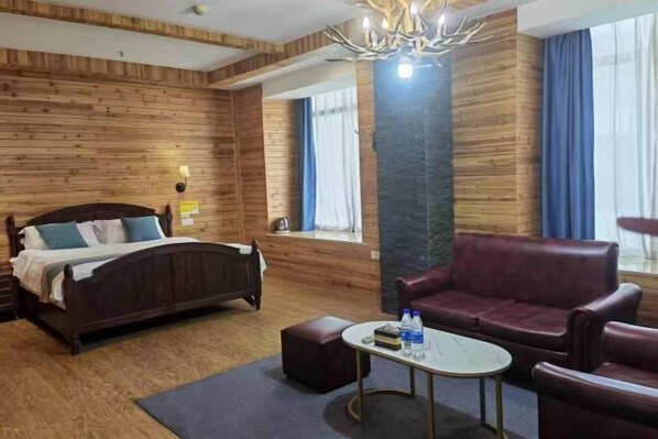 A wooden-paneled room with a bed, a red leather sofa, a small table, and a window with curtains. - K. Y. Hotel (Liuzhou)