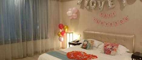 A bedroom with a bed, pillows, a nightstand, and a wall decoration.