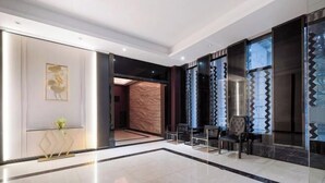 Una hall moderna con pavimento in marmo, reception e area salotto.