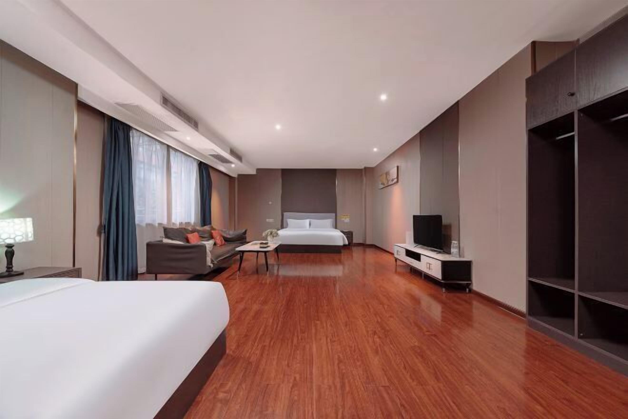 Una camera d'albergo con un letto, un divano, una TV, una scrivania e un armadio.