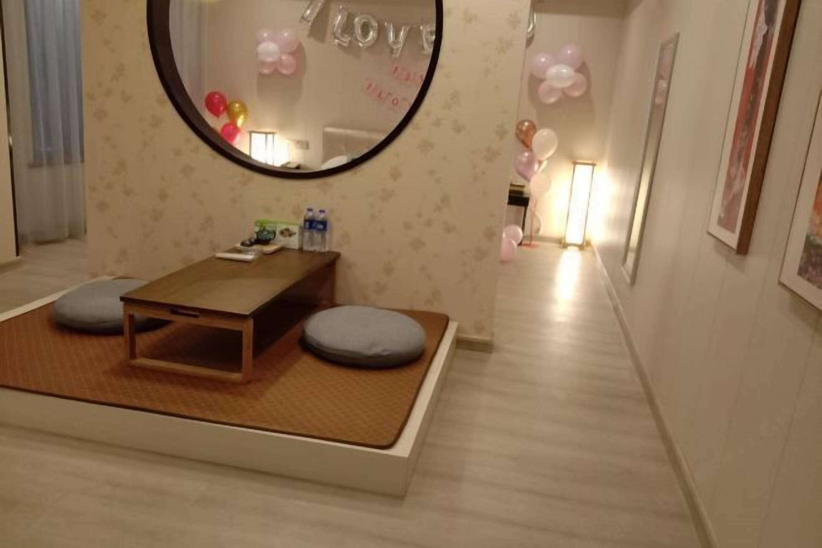 A room with a bed, a small wooden table, and a mirror.