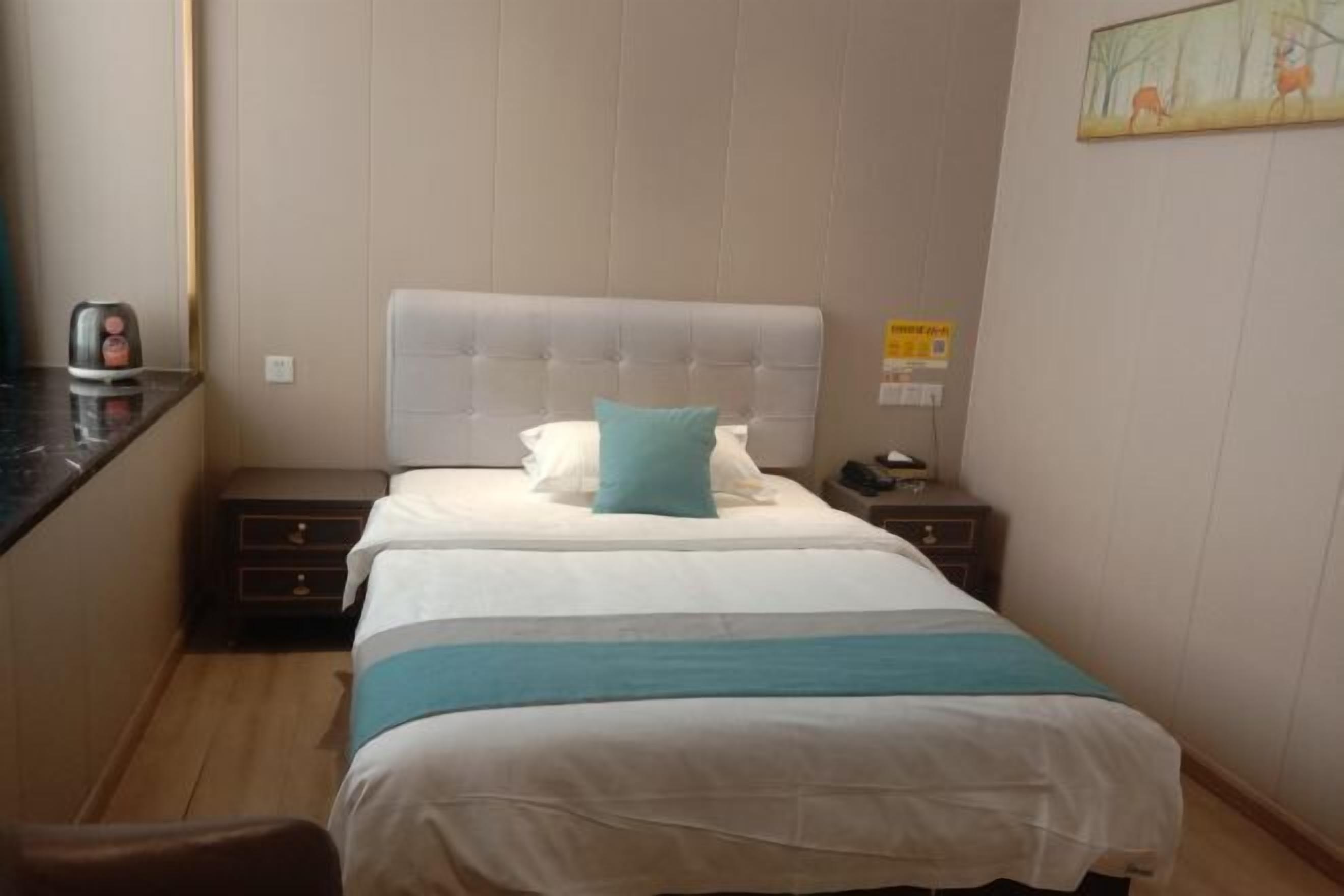 Une chambre d’hôtel avec un lit, une table de chevet, une machine à café et un tableau au mur.