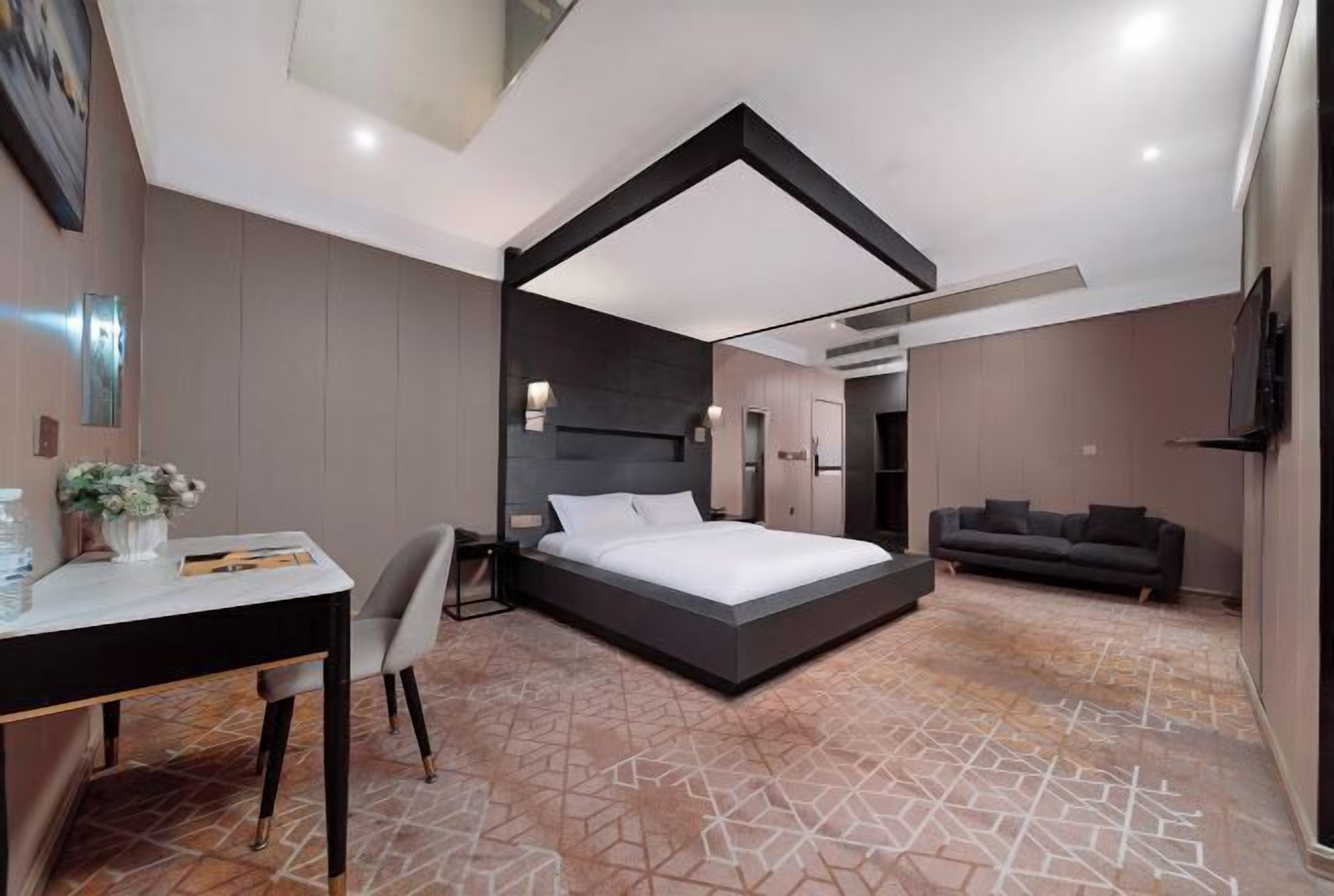 A modern hotel room with a bed, desk, and seating area.