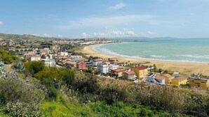 Un pueblo costero con playa, casas y un puente.