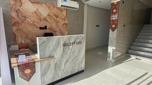 Een receptie met een marmeren wand, een receptiebalie en een trap.