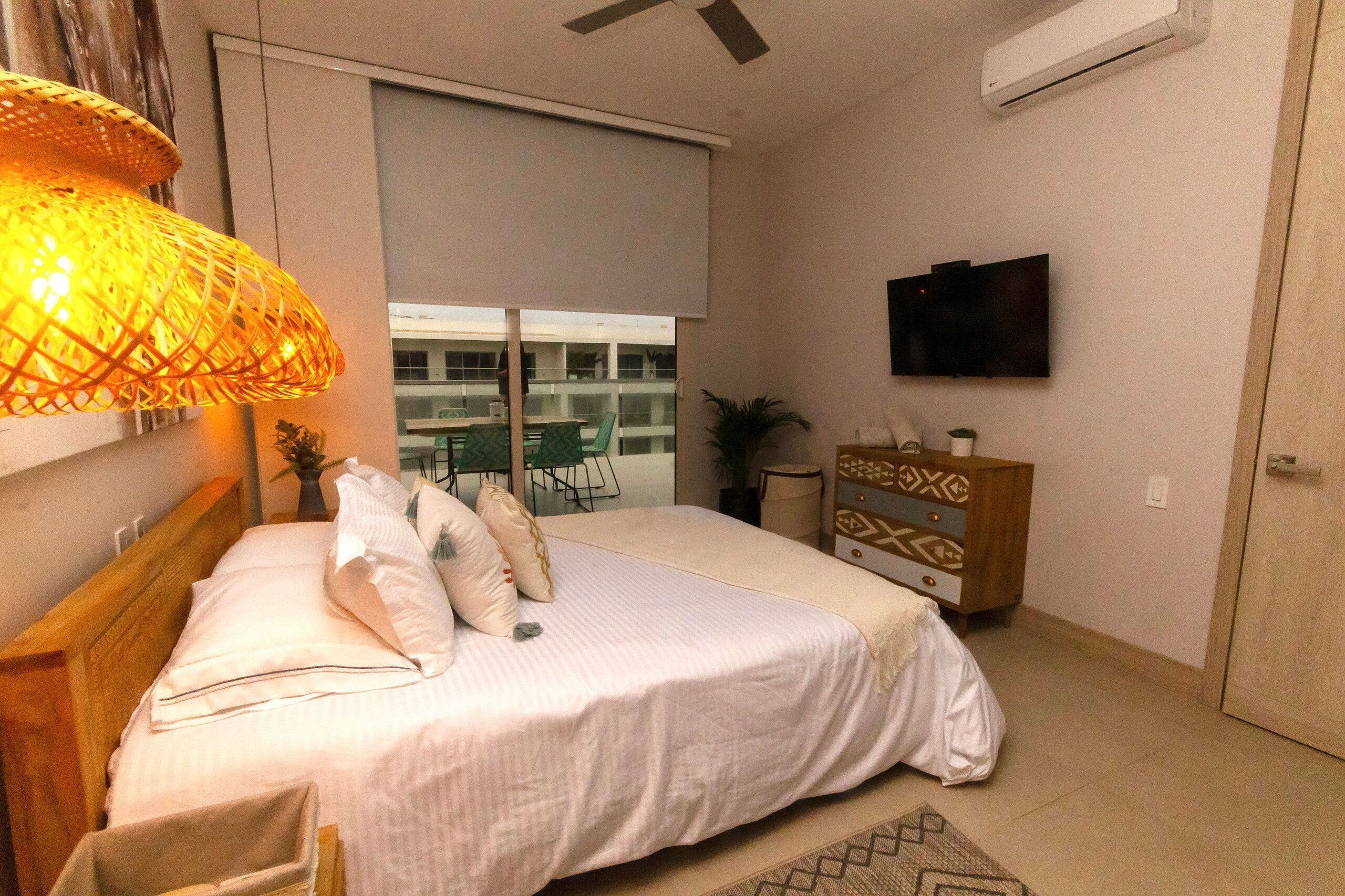 Ein Schlafzimmer mit Bett, Kommode, Fernseher und Deckenventilator.