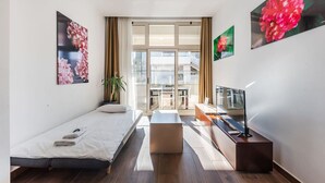 Una camera d'albergo moderna con un letto, una scrivania, una TV e ampie finestre.
