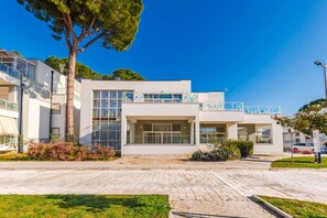 A modern building with a flat roof, large windows, and a paved entrance area.