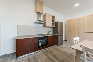 Een koelkast, een oven, een kookplaat, kookgerei, borden en bestek