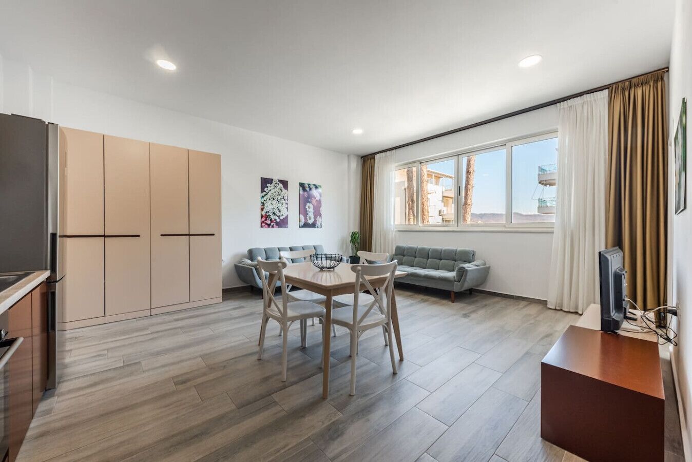 Un appartement moderne doté d’un coin repas, d’un canapé et de grandes fenêtres.