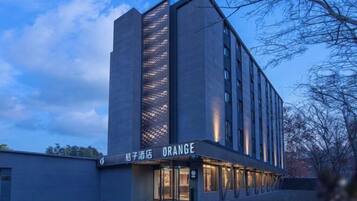 A modern hotel with a prominent vertical glass facade and the name "ORANGE" displayed on the ground floor.