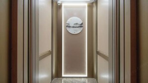 Un couloir étroit et bien éclairé, doté d’un sol en marbre et orné d’une œuvre d’art circulaire au mur.